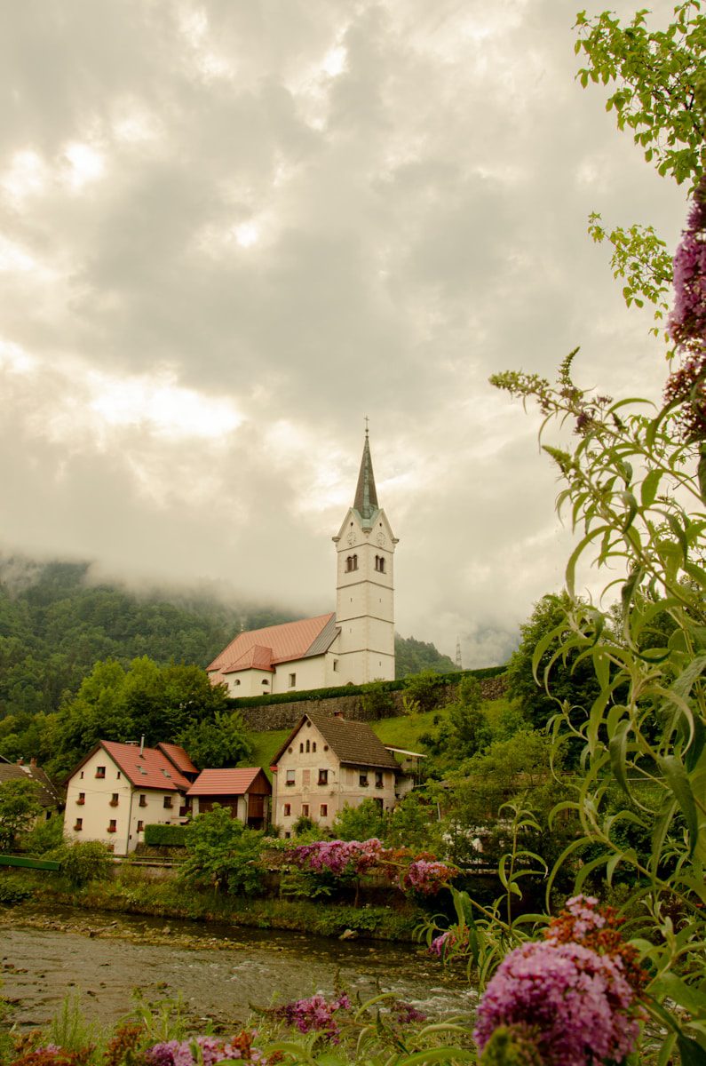 a church on a hill with a river in front of it