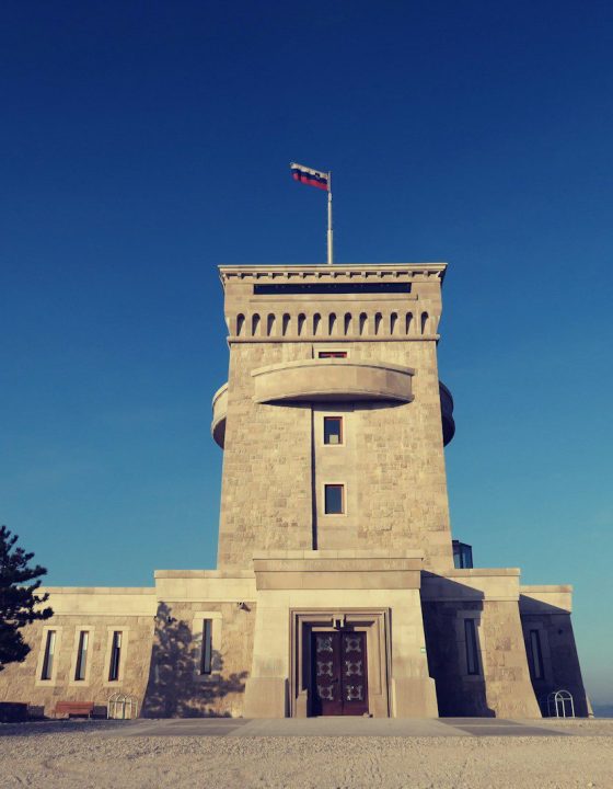 architectural photography of concrete building with flag on top