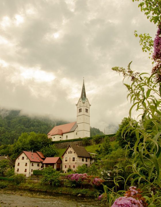 a church on a hill with a river in front of it