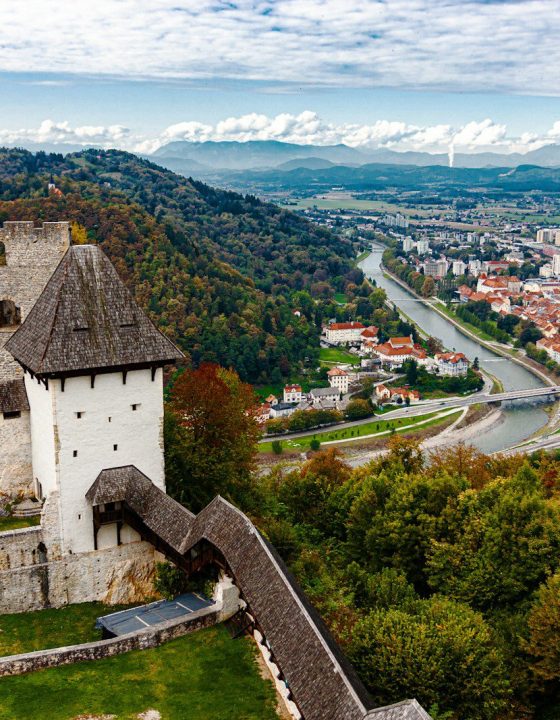 white and gray concrete house on green grass field near mountain under white clouds and blue
